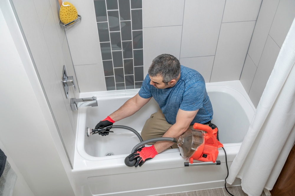 plumber cleaning a drain in bathroom
